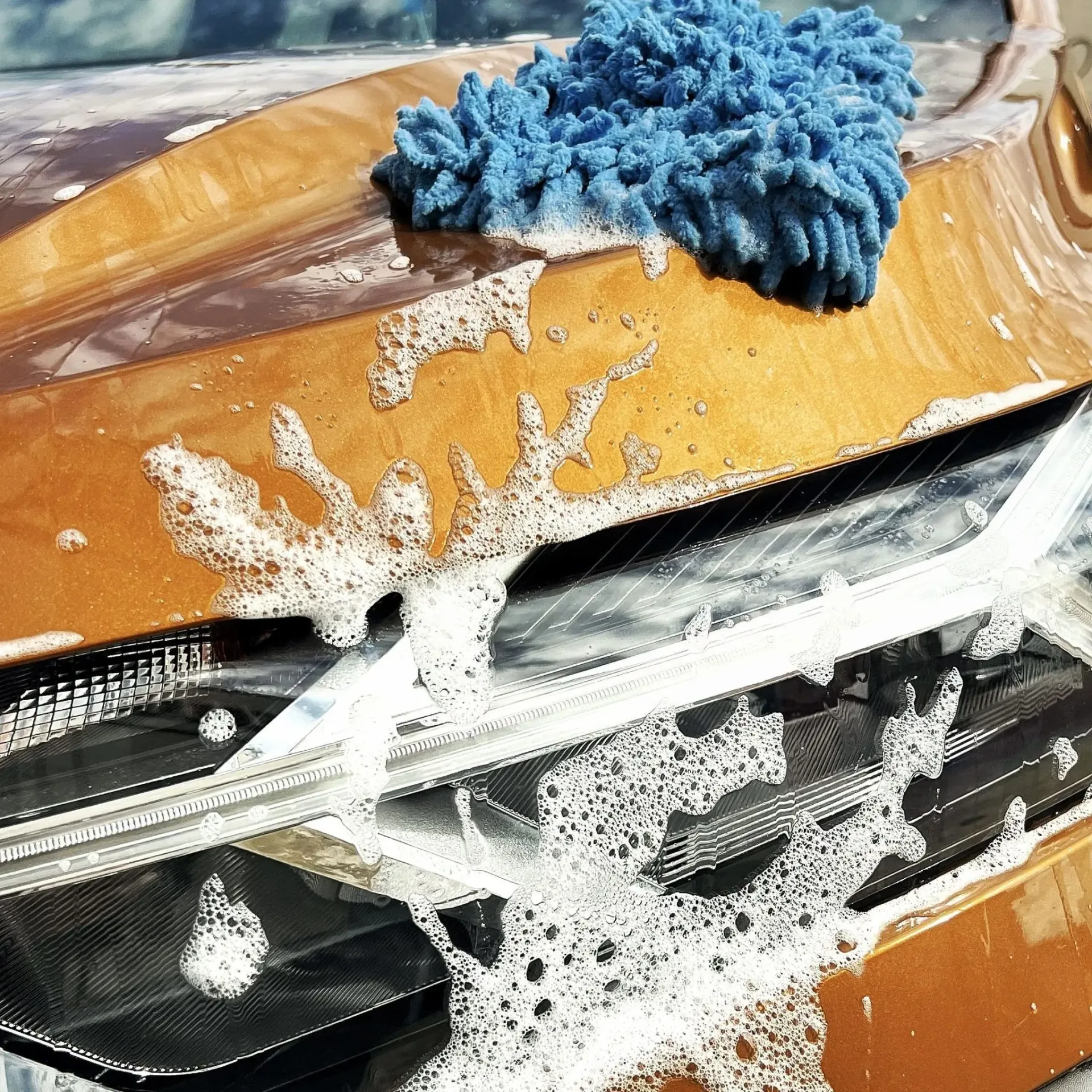 carrocería de coche con espuma y manopla encima del capó